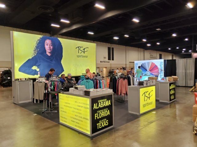 Example of how to display clothing at a trade show featuring a vibrant booth with assorted apparel neatly organized on racks.